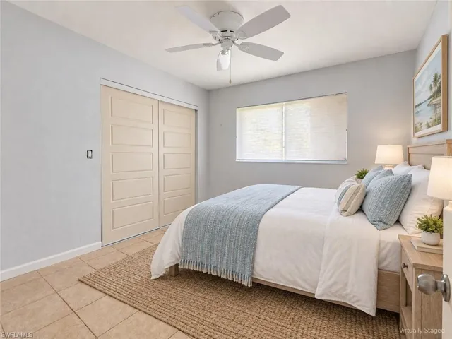 Neutral wall color, ceiling fan, window with blinds, panel closet doors, and tile flooring