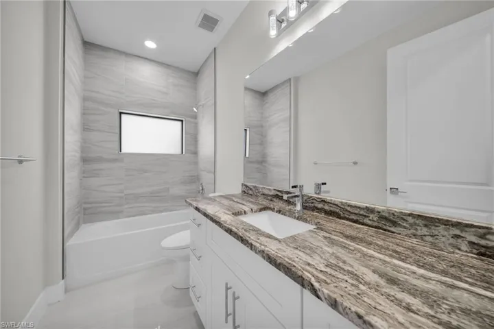 Full bathroom with vanity, bathing tub / shower combination, and recessed lighting