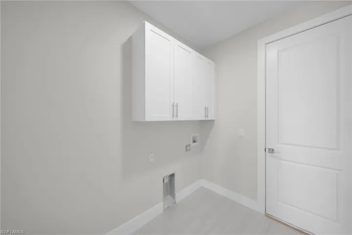 Washroom with washer hookup, cabinet space, and hookup for an electric dryer