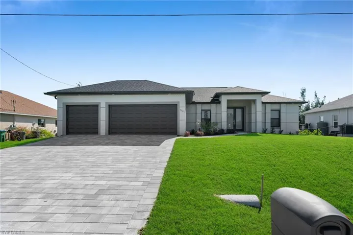 Prairie-style house with a front lawn, decorative driveway, stucco siding, and a garage