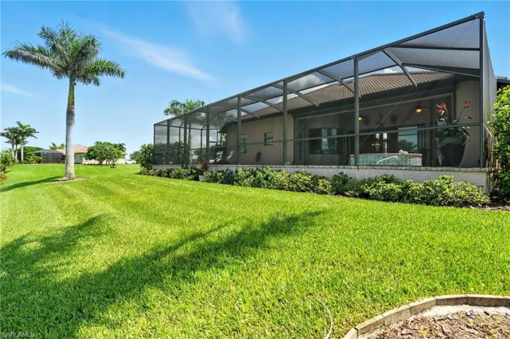 Back of house with a sunroom, glass enclosure, and a lawn