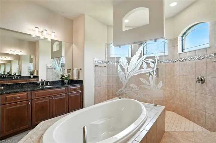 Bathroom featuring a bath, vanity, a walk in shower, and light tile patterned floors
