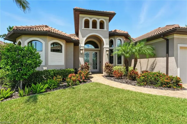 View of front of property with stucco siding, a front lawn, a tiled roof, a garage, and french doors