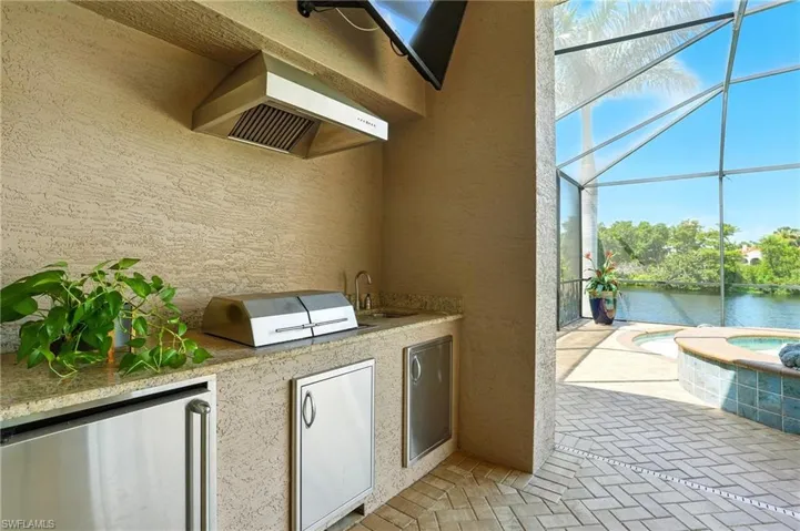 View of patio with a sunroom, a lanai, exterior kitchen, and a pool with connected hot tub