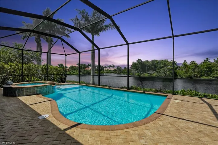 View of swimming pool featuring a pool with connected hot tub, a sunroom, a water view, and glass enclosure