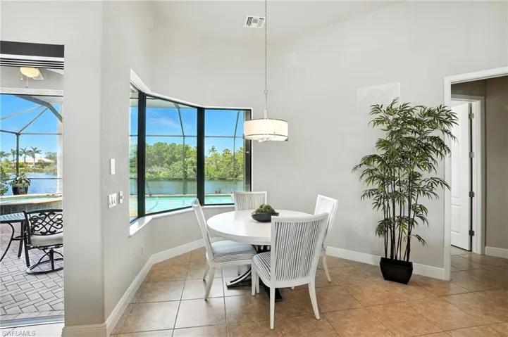 Dining space featuring a sunroom, light tile patterned floors, a water view, and a towering ceiling