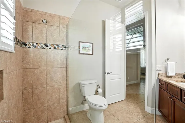 Bathroom featuring vanity, a stall shower, light tile patterned flooring, and healthy amount of natural light