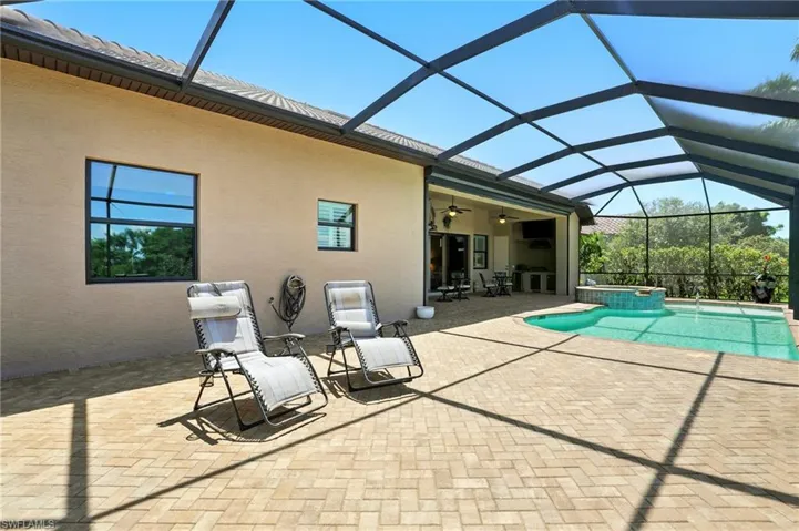 Rear view of property featuring a sunroom, a patio area, stucco siding, a lanai, and a pool with connected hot tub