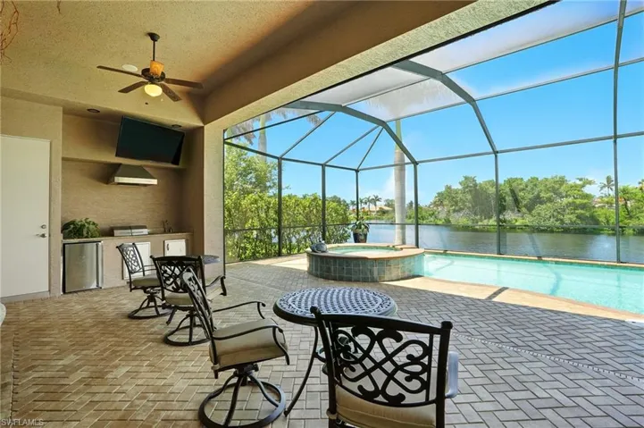 View of patio featuring an outdoor kitchen, a sunroom, a pool with connected hot tub, a lanai, and a ceiling fan