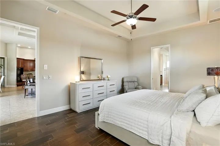 Bedroom featuring wood tiled floors, a raised ceiling, and ceiling fan