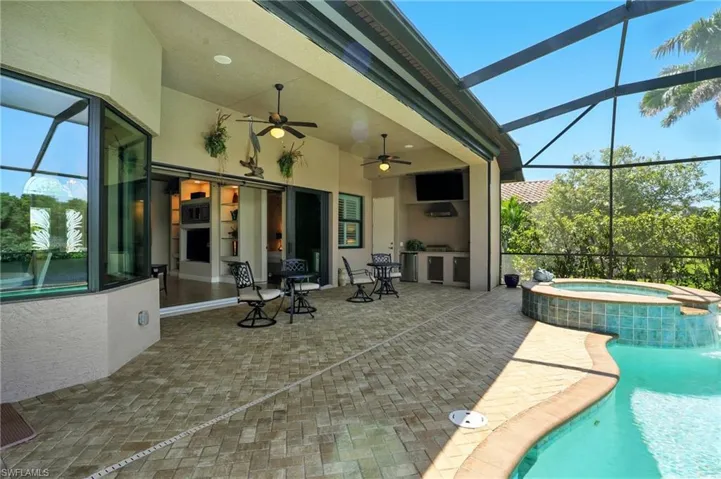 View of patio with a sunroom, glass enclosure, ceiling fan, and a pool with connected hot tub