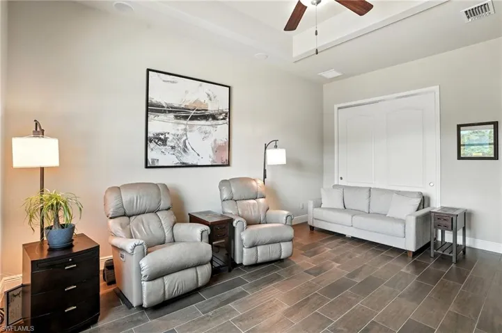Living area featuring wood finish floors, a ceiling fan, and a tray ceiling
