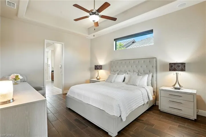 Bedroom featuring a tray ceiling, wood tiled floors, and ceiling fan