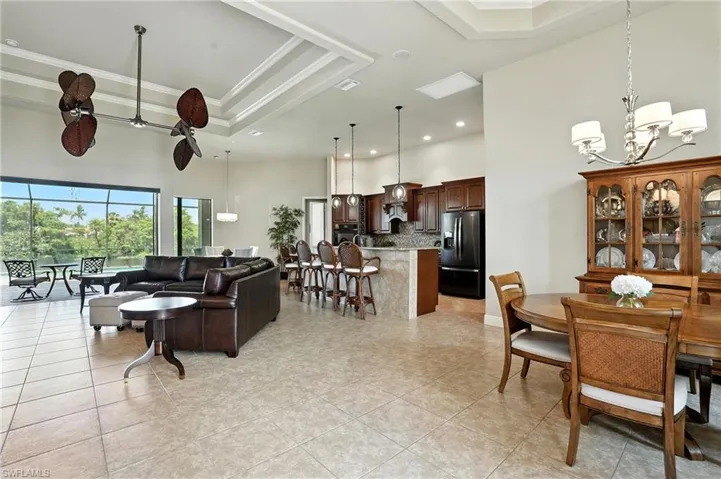 Dining room featuring a towering ceiling, a raised ceiling, a chandelier, ornamental molding, and light tile patterned floors