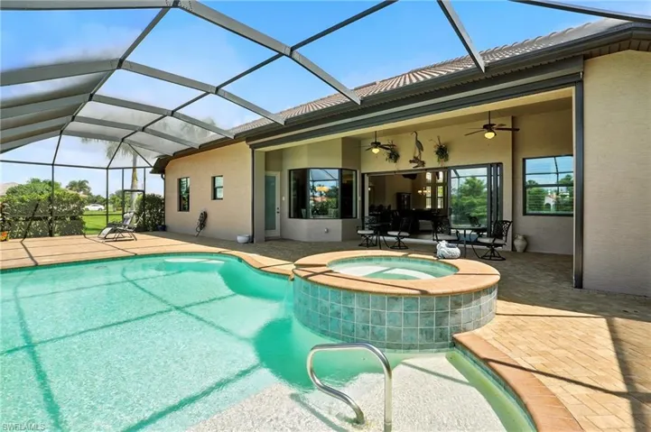 View of pool featuring a patio area, a sunroom, a lanai, a pool with connected hot tub, and a ceiling fan