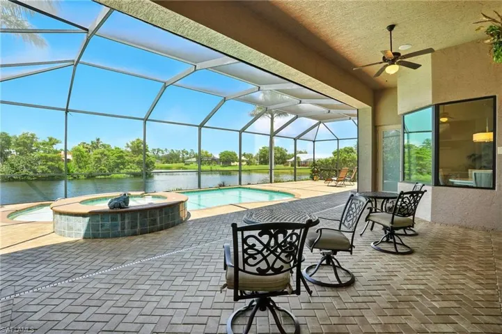 View of patio / terrace featuring a sunroom, a pool with connected hot tub, a lanai, a ceiling fan, and a water view