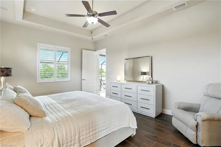 Bedroom with wood tiled floors, a raised ceiling, and a ceiling fan