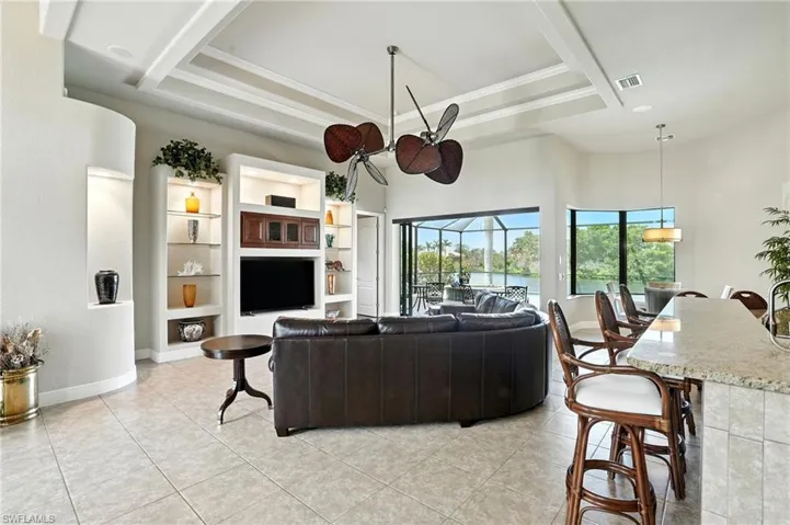 Living room with a sunroom, a tray ceiling, light tile patterned floors, a high ceiling, and ornamental molding