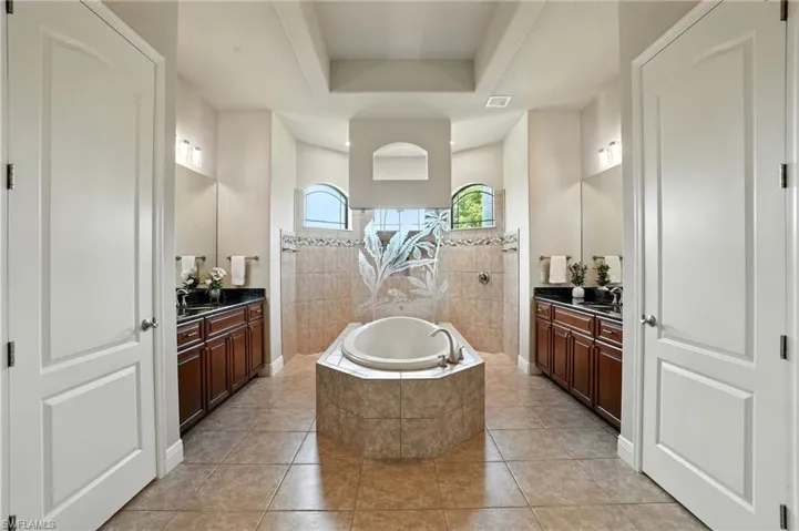 Full bath with a walk in shower, two vanities, a bath, and light tile patterned floors
