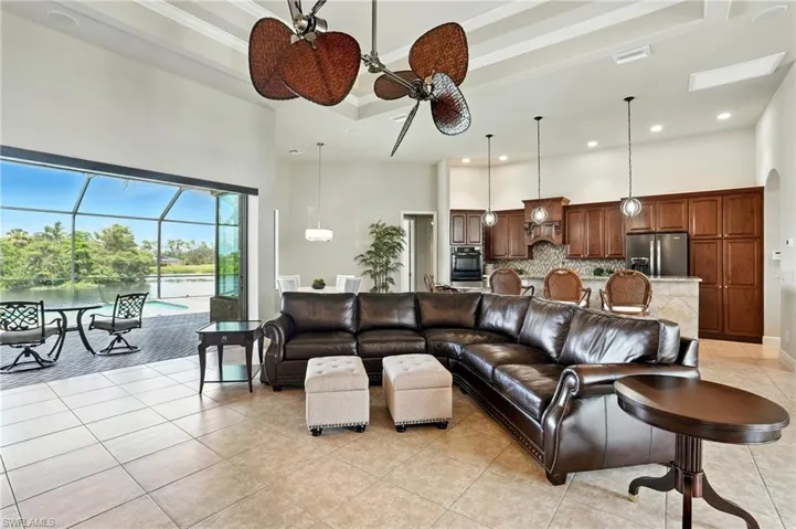 Living room featuring a sunroom, a high ceiling, light tile patterned floors, a water view, and ceiling fan