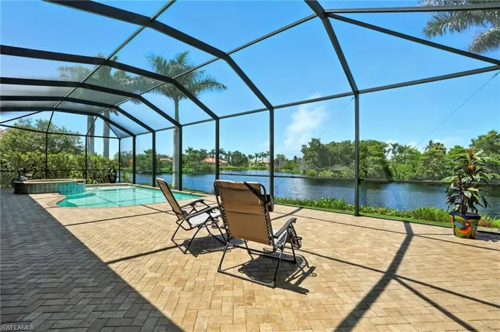 View of swimming pool with a pool with connected hot tub, glass enclosure, a sunroom, a water view, and a patio