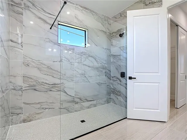 Full bathroom with a marble finish shower and a walk in closet