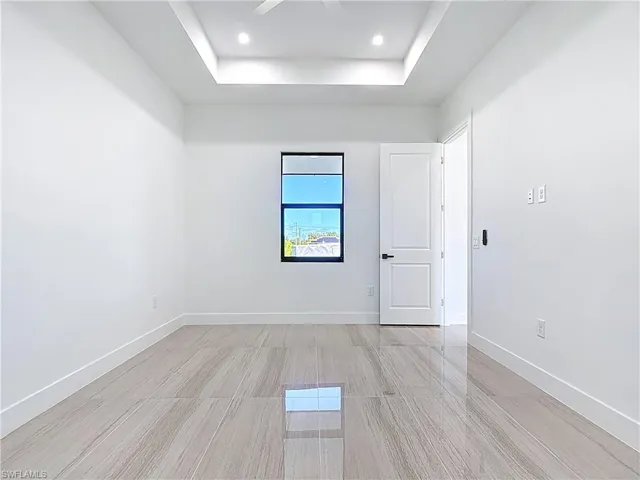 Spare room with a raised ceiling, light wood finished floors, recessed lighting, and ceiling fan