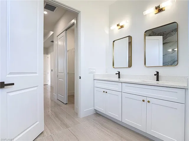 Bathroom with double vanity and a walk in closet