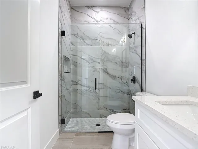 Full bath featuring a marble finish shower and vanity