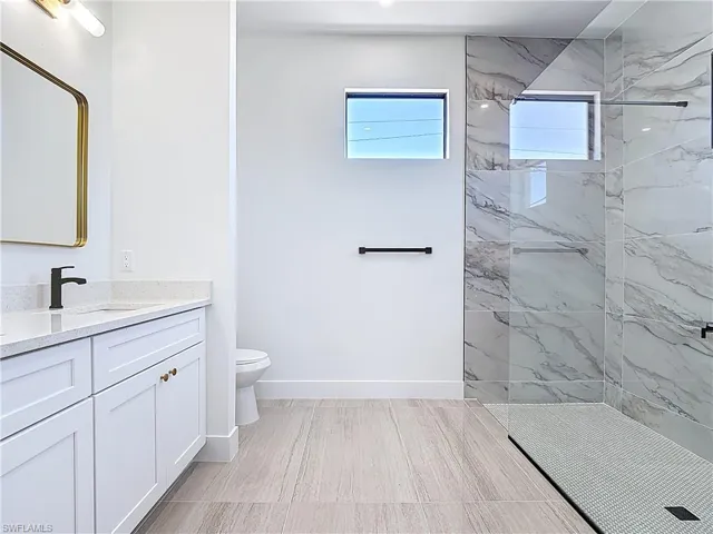 Full bath with vanity, a marble finish shower, and light wood finished floors