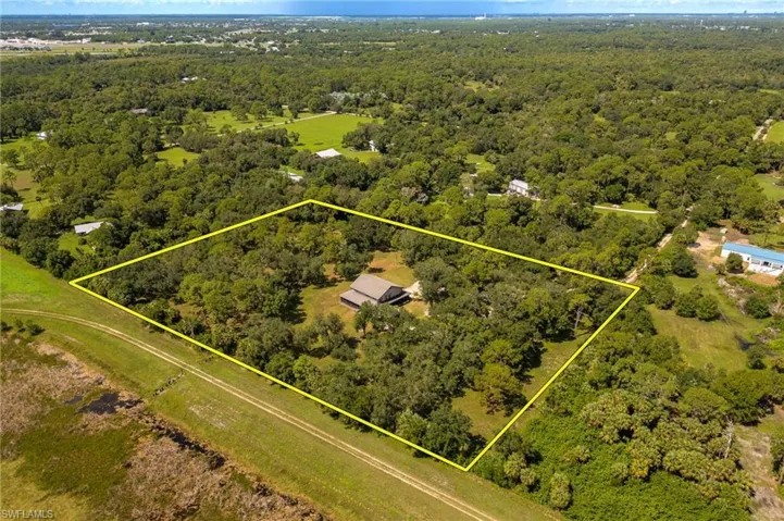 Aerial view of property's location with property parcel outlined and a heavily wooded area