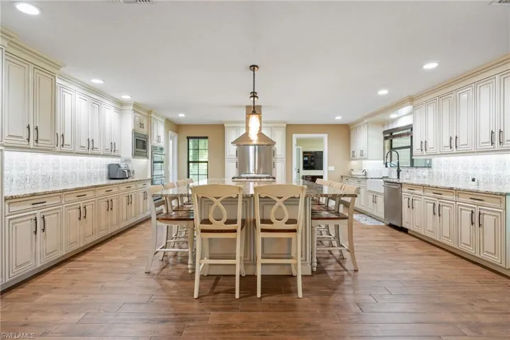 Kitchen with tasteful backsplash, cream cabinetry, pendant lighting, light stone counters, and recessed lighting