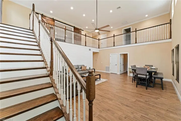 Stairway featuring ornamental molding, wood finished floors, a towering ceiling, recessed lighting, and ceiling fan
