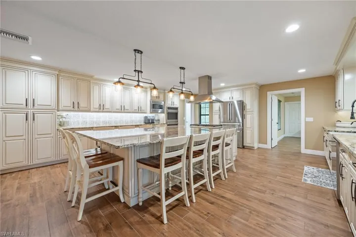 Kitchen with backsplash, a kitchen breakfast bar, pendant lighting, a center island, and light stone counters