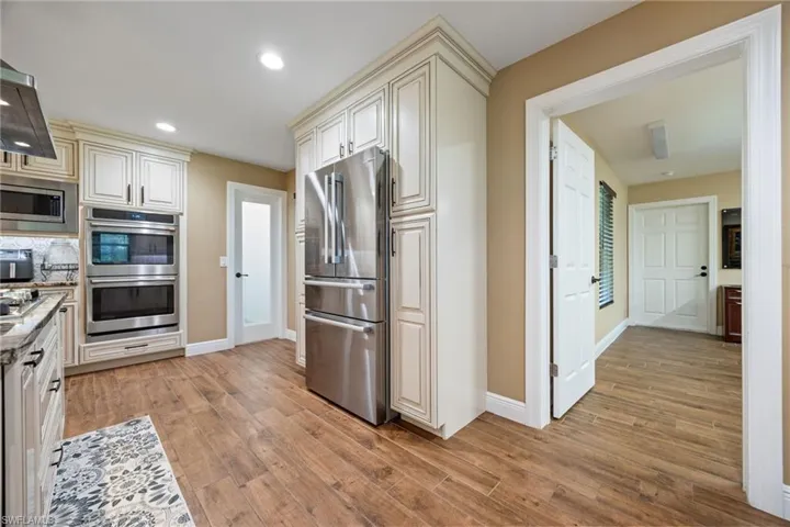 Kitchen featuring stainless steel appliances, light wood finished floors, cream cabinetry, recessed lighting, and light stone counters