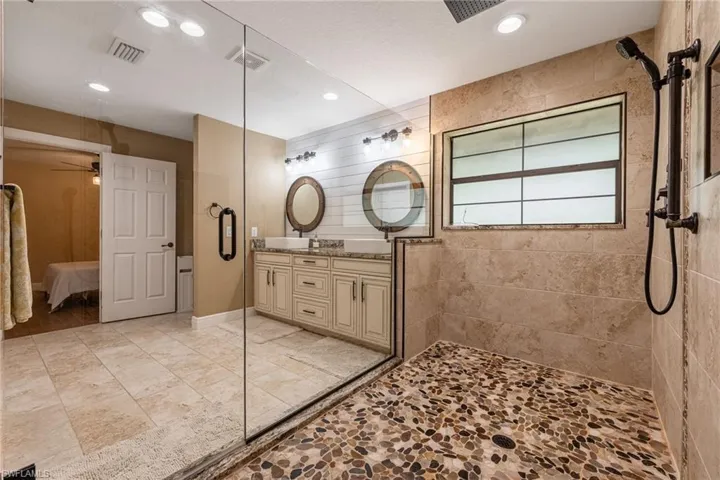 Ensuite bathroom featuring double vanity, walk in shower, recessed lighting, and a ceiling fan