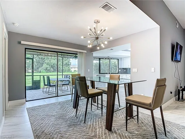 Dining area with light marble finish flooring and a chandelier