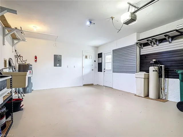 Garage featuring electric panel, water heater, and a garage door opener