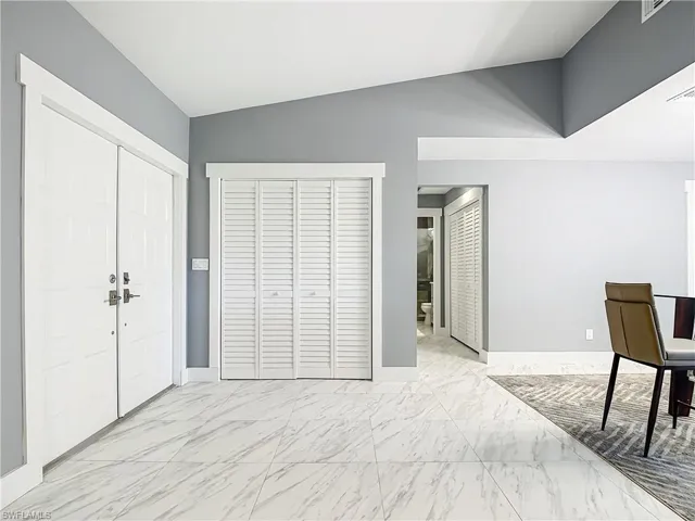 Bedroom featuring light marble finish flooring, two closets, lofted ceiling, and connected bathroom