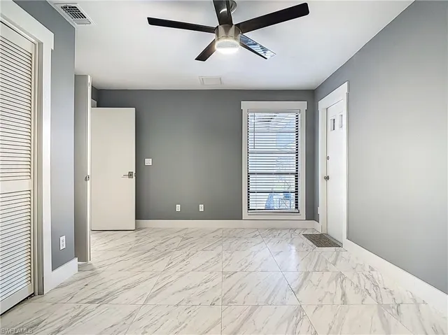 Unfurnished room with light marble finish floors and ceiling fan