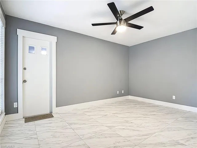 Unfurnished room with light marble finish flooring and ceiling fan