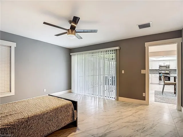 Unfurnished bedroom with access to exterior, ceiling fan, and marble look tile flooring