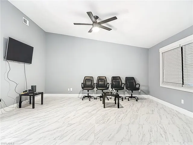 Office area with ceiling fan and light marble finish flooring