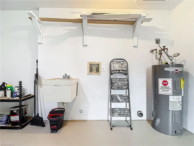 Utility room featuring electric water heater and a sink