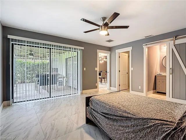 Bedroom featuring a barn door, access to outside, a ceiling fan, and ensuite bathroom