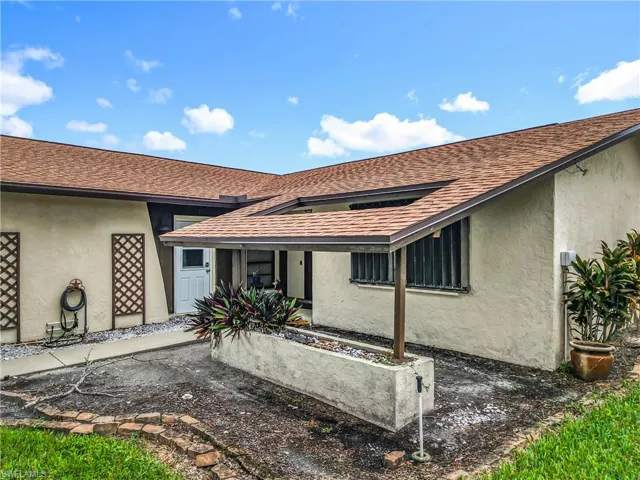 Rear view of house featuring stucco siding and a shingled roof