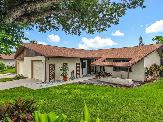 Single story home featuring a shingled roof, a front yard, stucco siding, driveway, and a garage