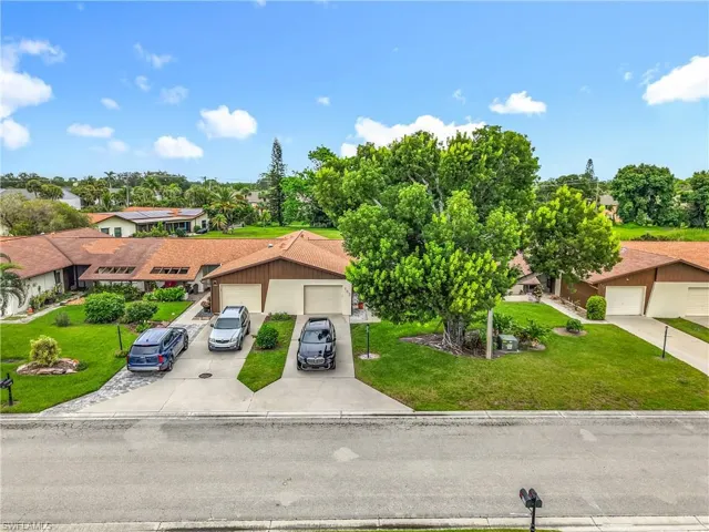 View of front of property featuring a garage, a front lawn, concrete driveway, and a residential view
