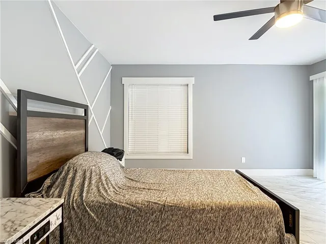 Bedroom with ceiling fan and marble look tile flooring