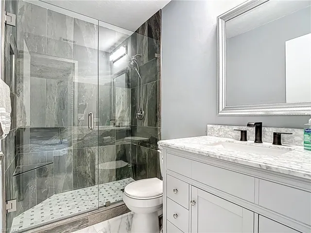 Bathroom featuring vanity, a stall shower, and marble look tiles